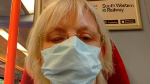 on a train wearing a mask